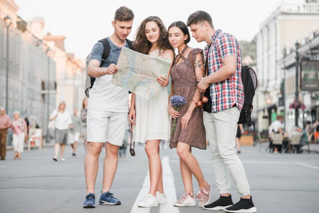 Four young adults examine a map together on a busy city street.