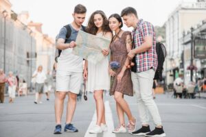 Four young adults examine a map together on a busy city street.