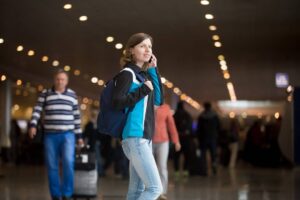 Young woman walking in an airport terminal, talking on her mobile phone.