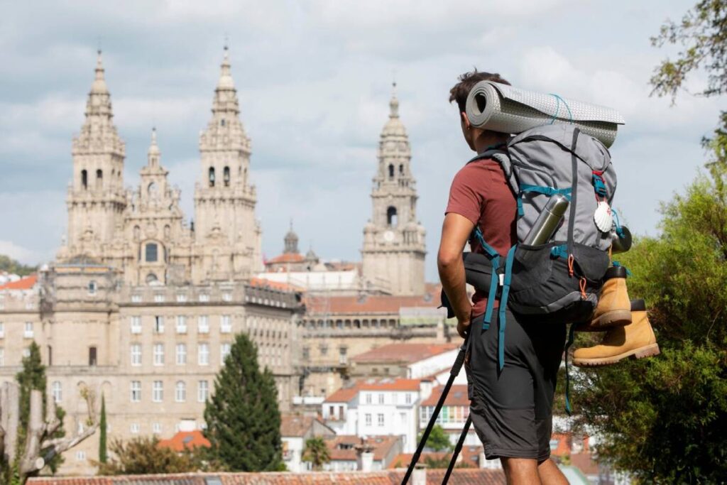 A hiker with a backpack viewing the twin-towered cathedral in a historic city.