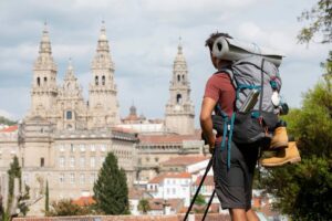 A hiker with a backpack viewing the twin-towered cathedral in a historic city.