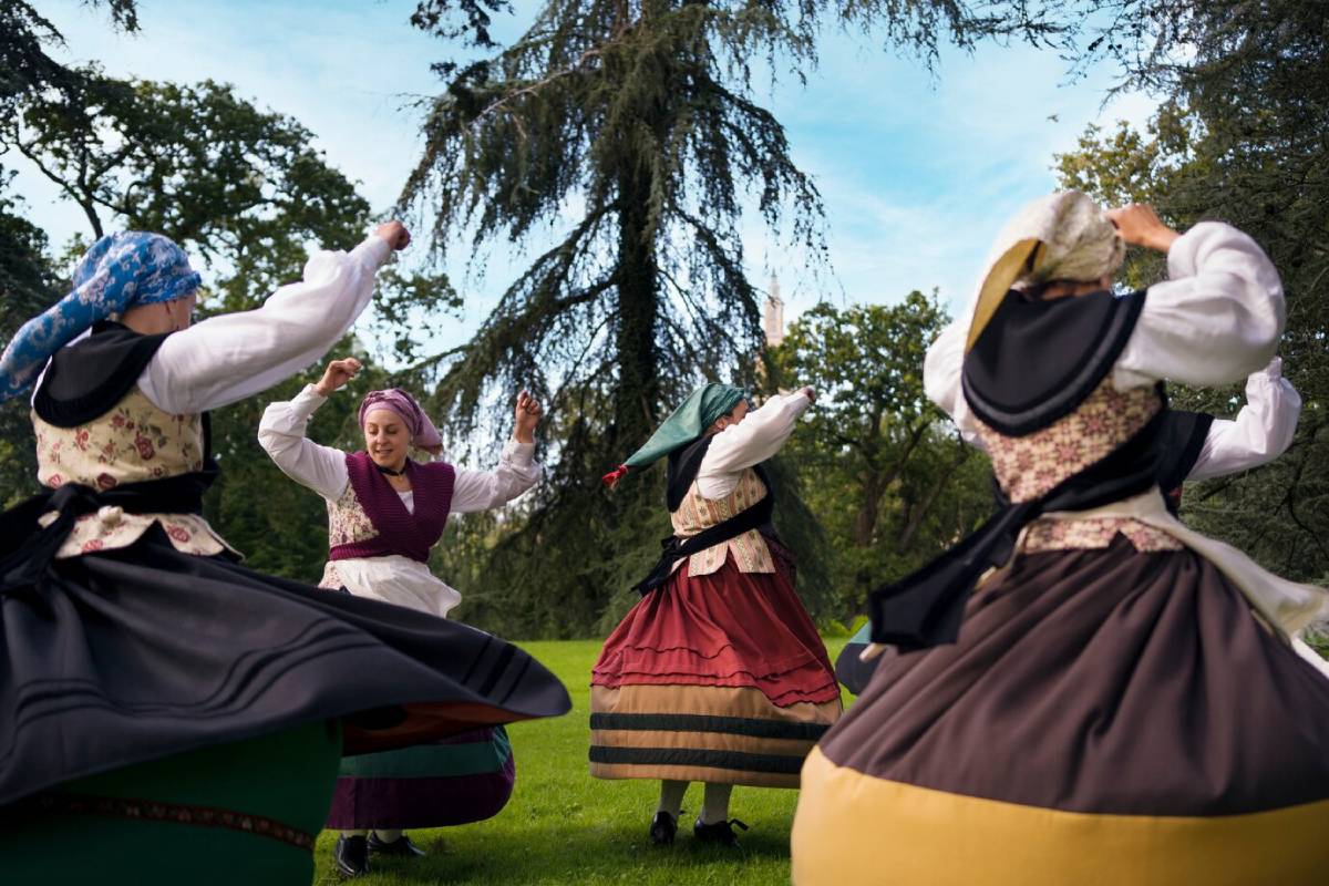  Traditional dancers in folk costumes performing in a park, swirling with visible joy.