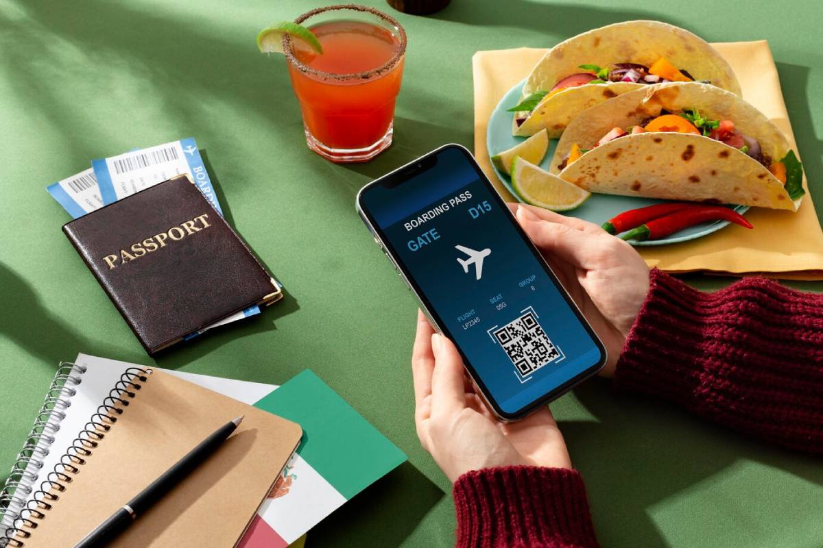 Person holding a smartphone displaying a boarding pass, with passport, drink, and tacos on a table.