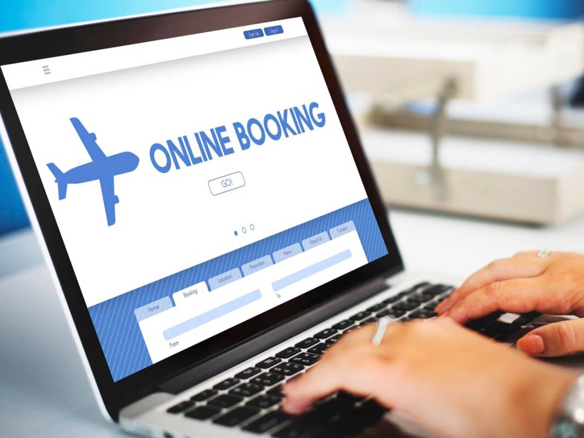 Person booking a flight online on a laptop displaying