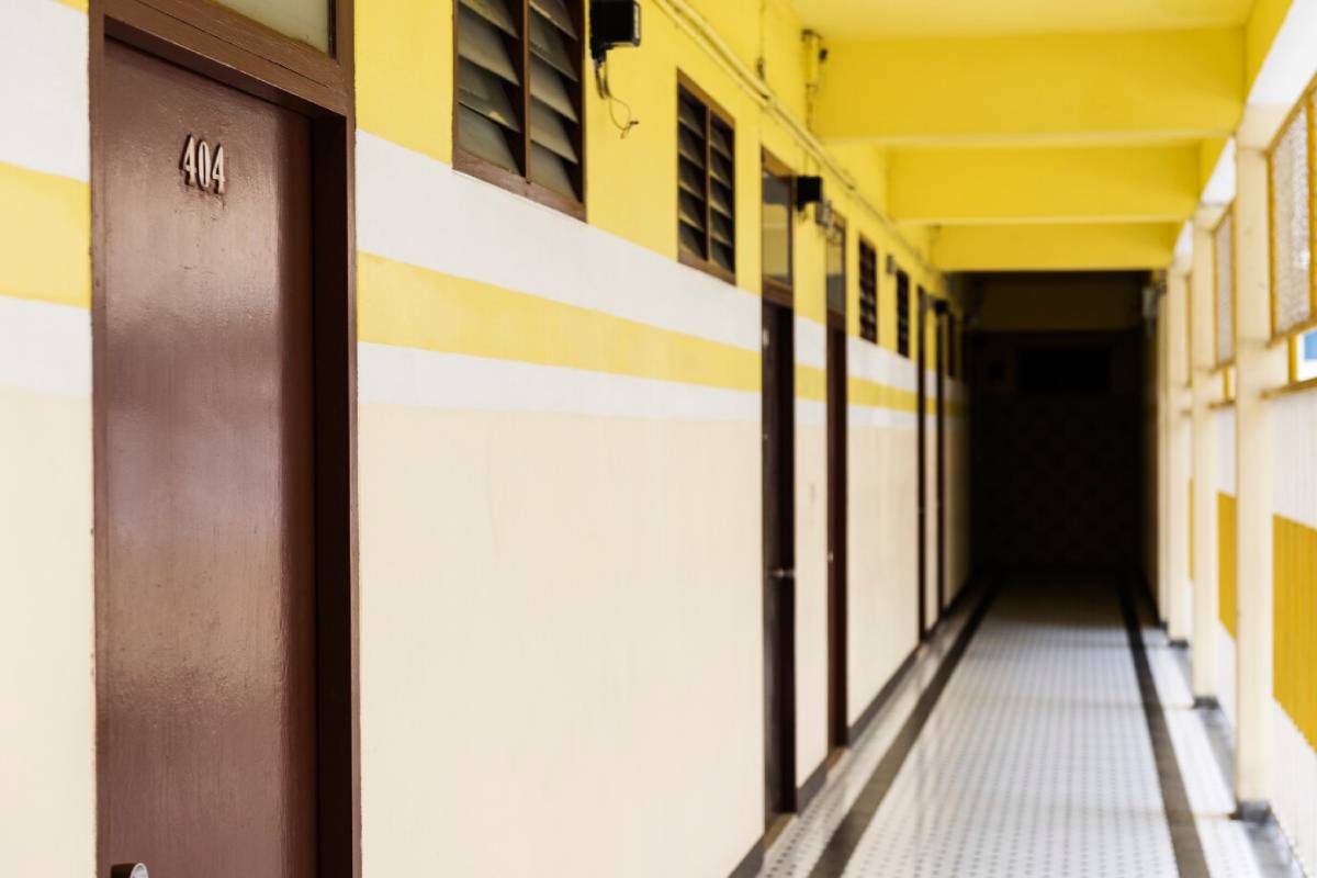  A narrow corridor in a building lined with yellow painted walls and numbered brown doors.