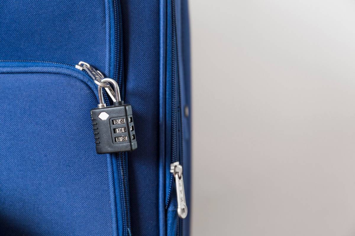  Combination padlock securing a zipper on a blue fabric suitcase.