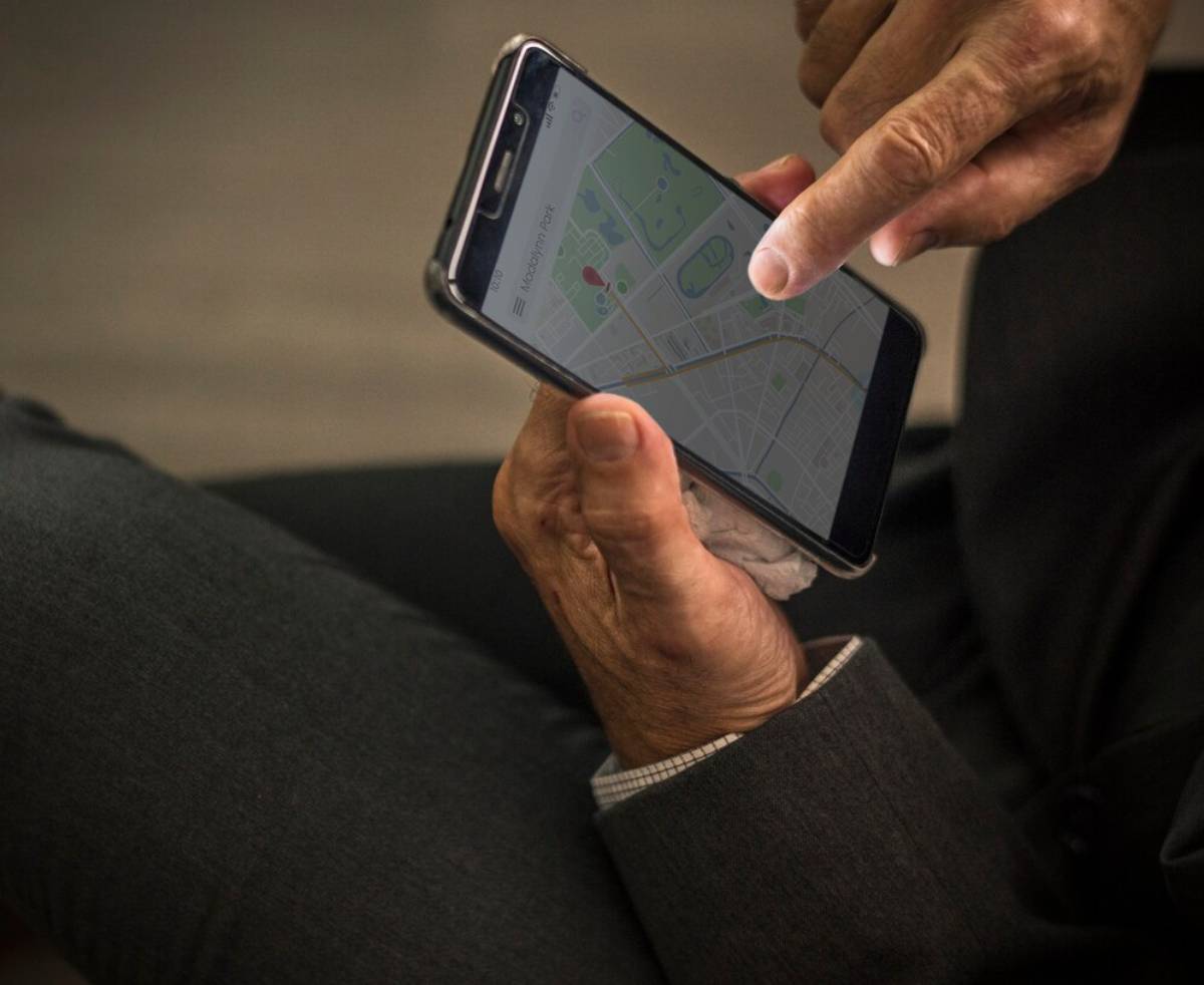  An older person using a smartphone to view a map application, focusing on their hands and the device.