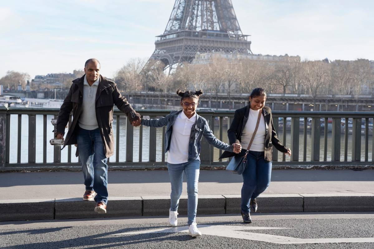  A family walks hand-in-hand near the Eiffel Tower on a sunny day.